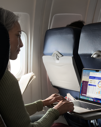 A person using a MacBook Air while sitting on an airplane, to demonstrate the device's long battery life