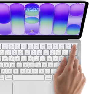 MacBook Neo, silver color, showing login screen, person's finger on Touch ID sensor in top-right corner of keyboard